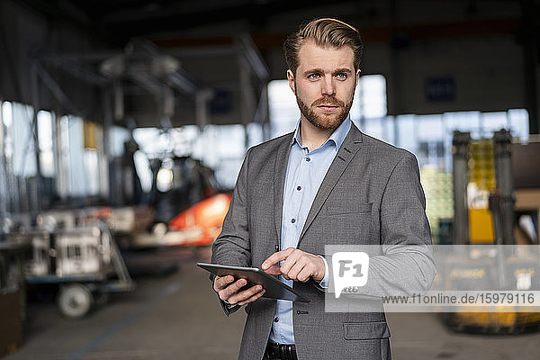 Portrait of a young businessman with tablet in a factory