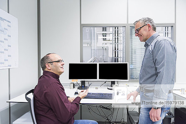 Two smiling colleagues talking in factory office