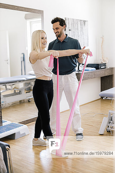 Physiotherapist assisting female patient  practicing with fitness band