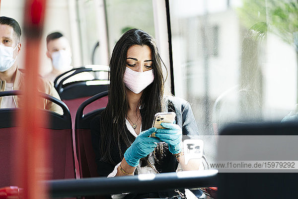 Portrait of young woman wearing protective mask in bus looking at cell phone Spain