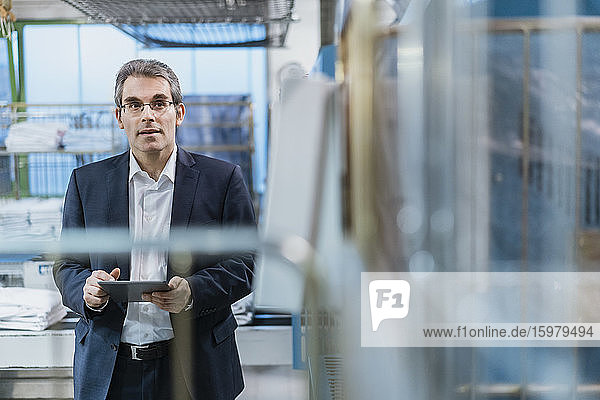 Portrait of a mature businessman holding tablet in a factory
