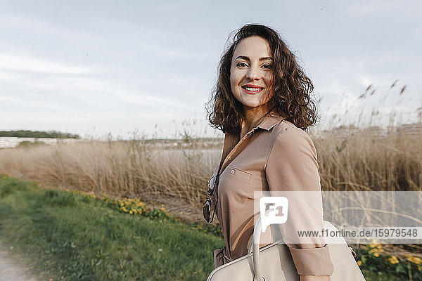 Happy businesswoman carrying laptop bag while standing by field