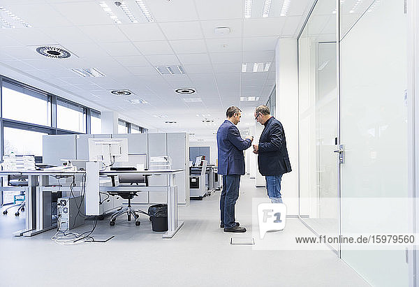 Two businessmen standing in office looking at smartphone