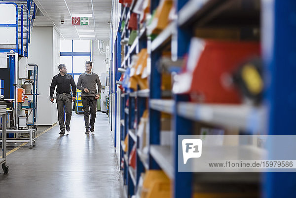 Two men walking and talking in factory