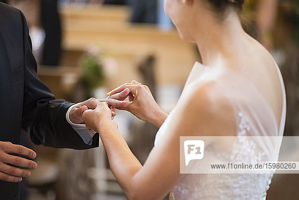 Bride wearing wedding ring to bridegroom while standing in church