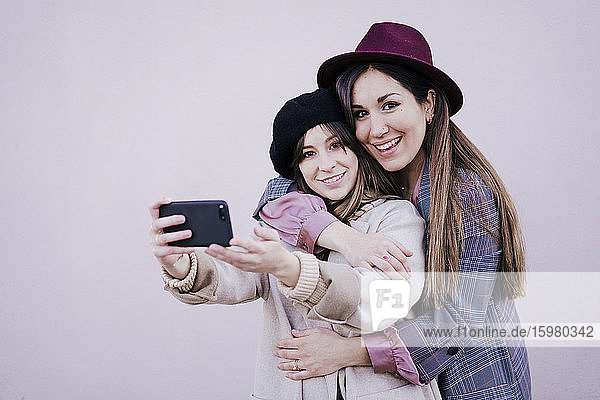 Porträt von zwei glücklichen Frauen  die ein Selfie mit einem Smartphone machen