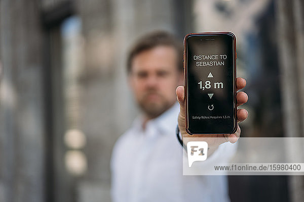 Close-up of man holding smartphone showing distance on display