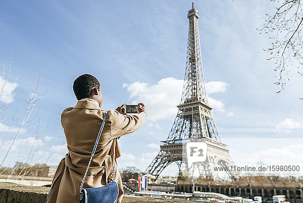 Frau fotografiert den Eiffelturm mit ihrem Smartphone gegen den Himmel  Paris  Frankreich