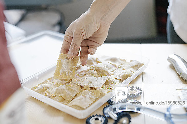 Hand of woman holding ravioli pasta in kitchen at home