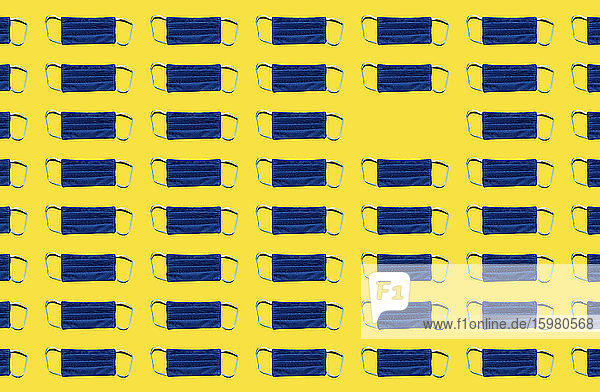 Pattern of blue protective face masks against yellow background 