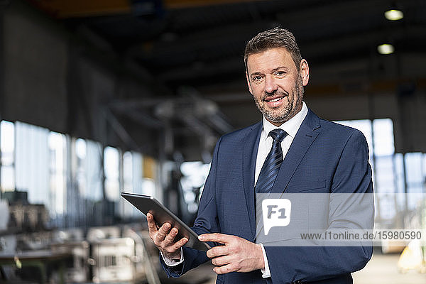 Portrait of a confident businessman with tablet in a factory