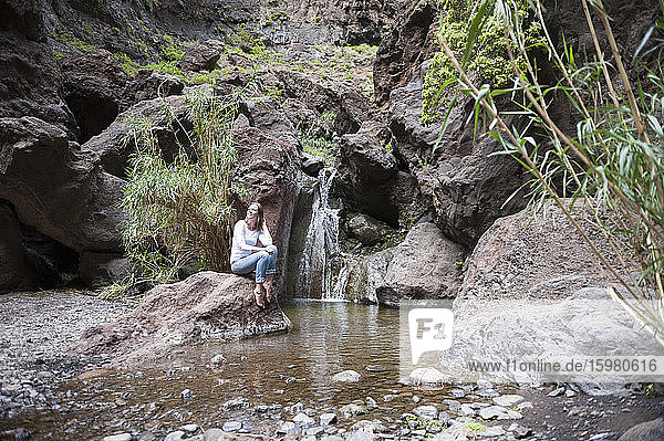 Female hiker sitting at waterfall  Tenerife  Balearic Islands  Spain