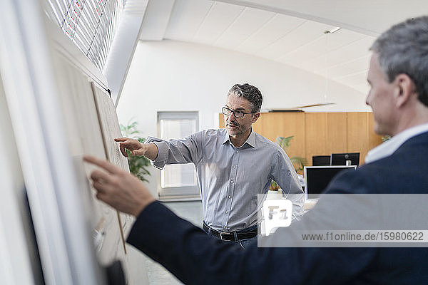 Mature male entrepreneur pointing while explaining strategy to businessman at office during meeting