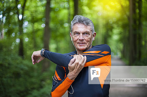 Porträt eines selbstbewussten älteren aktiven Mannes  der sich im Park streckt