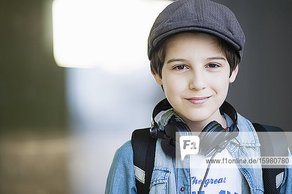 Selbstbewusster Junge mit Kopfhörern um den Hals im Freien