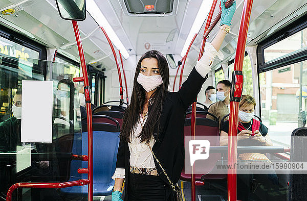 Porträt einer jungen Frau mit Schutzmaske und Handschuhen in einem öffentlichen Bus  Spanien