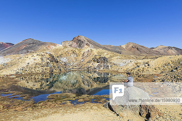 New Zealand  North Island  Male hiker relaxing at Emerald Lakes in North Island Volcanic Plateau
