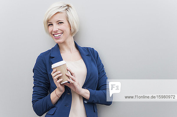 Portrait of blond businesswoman with coffee to go