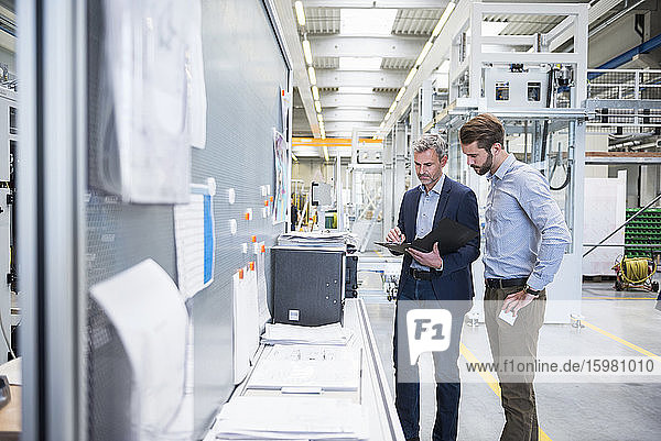 Two businessmen with folder in a factory