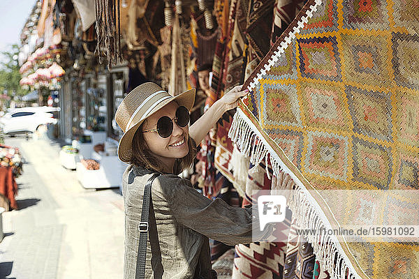 Lächelnde junge Frau beim Kauf eines Schals an einem Marktstand in Goreme  Kappadokien  Türkei