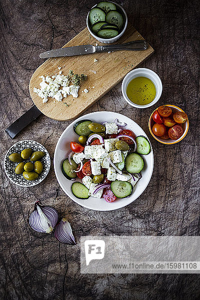 Schüssel mit verzehrfertigem griechischem Salat und seinen Zutaten