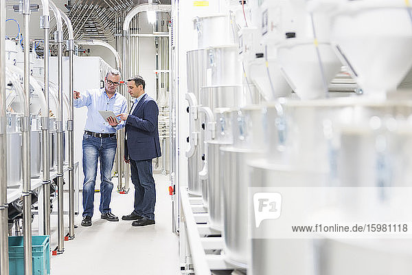Two businessmen with tablet having a discussion in a factory