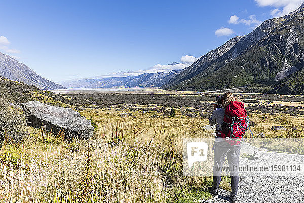 New Zealand  Oceania  South Island  Canterbury  Ben Ohau  Southern Alps (New Zealand Alps)  Mount Cook National Park  Rear view of tourist photographing Tasman Valley