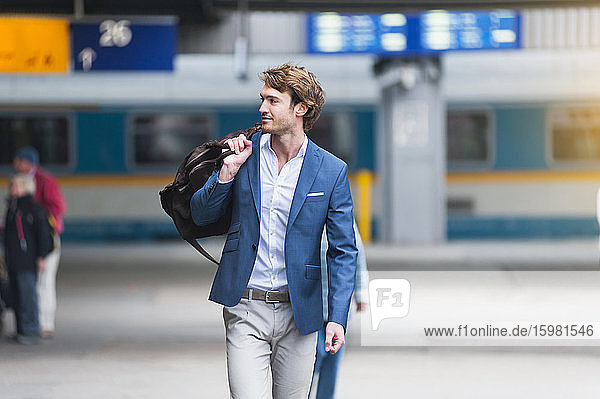 Porträt eines jungen Geschäftsmannes mit Tasche am Bahnhof