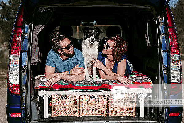 Entspanntes Paar mit Hund im Kofferraum eines Minivans