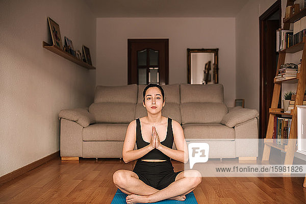 Confident woman meditating in prayer position at home