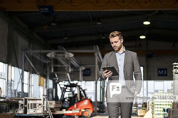 Young businessman using tablet in a factory