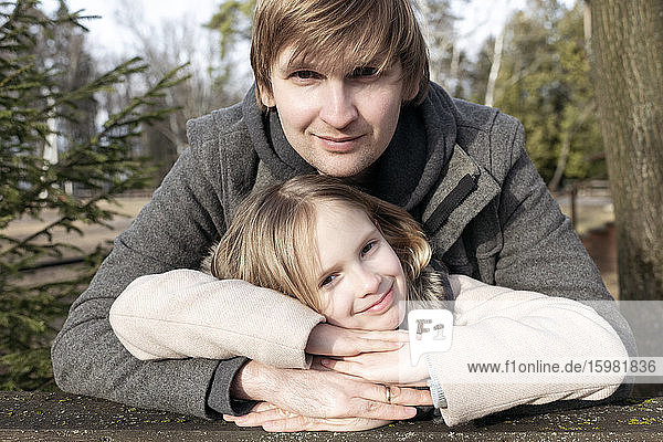 Porträt eines lächelnden Mädchens  das sich auf die Hände seines Vaters stützt  in einem Hinterhof an einem sonnigen Tag  Tarusa  Russland