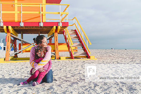 Loving mother embracing daughter at Miami beach Florida USA