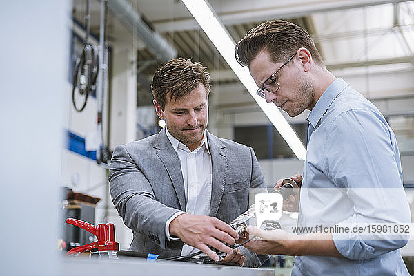 Two businessmen examining a product in a factory