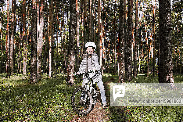 Glücklicher Junge mit Fahrrad im Wald