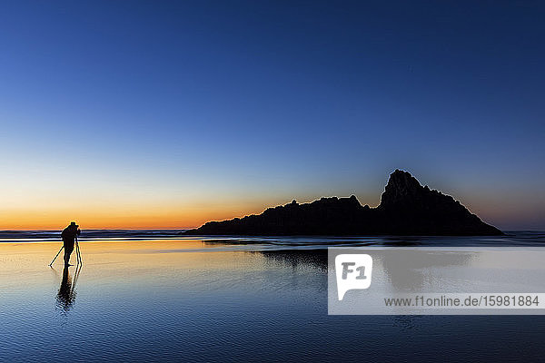 Tourist beim Fotografieren am Strand von Karekare gegen den klaren Himmel bei Sonnenuntergang  Neuseeland