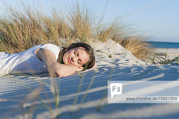 Porträt einer lächelnden Frau mit geschlossenen Augen  die sich am Strand entspannt  Sardinien  Italien