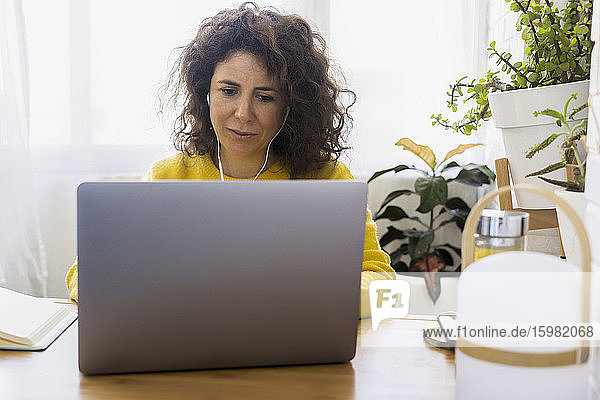 Woman using laptop at desk in home office