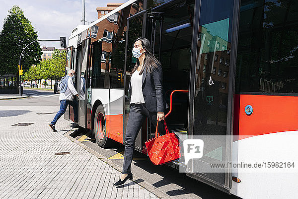 Frau mit Schutzmaske beim Aussteigen aus einem öffentlichen Bus  Spanien