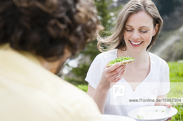 Lächelnde schöne Frau  die einen Snack isst  während sie ein Picknick mit einem Mann genießt