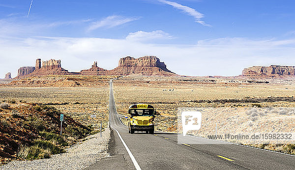 School bus on desert road at Monument Valley Tribal Park against sky  Utah  USA