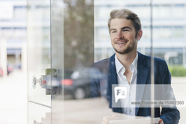 Smiling young businessman using tablet in the city
