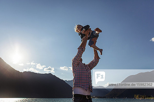 Vater hält seine Tochter gegen den blauen Himmel am Achensee  Bundesland Tirol  Österreich