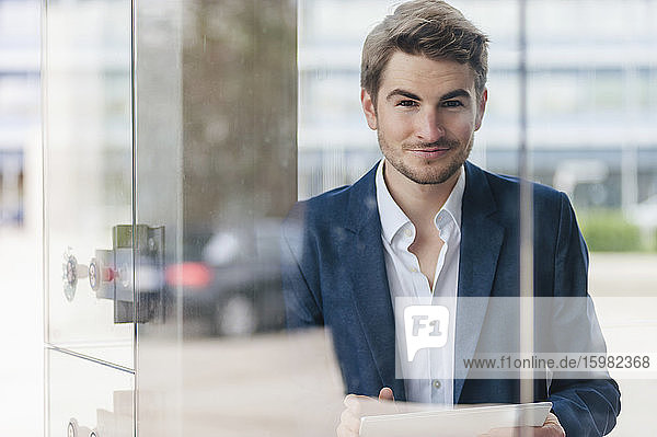 Porträt eines jungen Geschäftsmannes  der ein Tablet in der Stadt benutzt