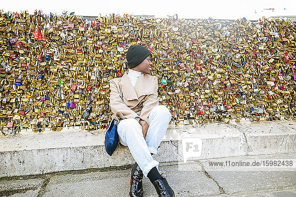 Junge Frau sitzt gegen Liebesschlösser auf einer Brücke  Paris  Frankreich