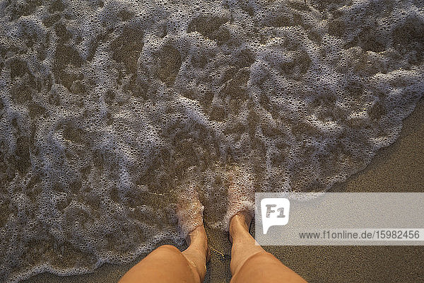 Feet of woman standing at seafront