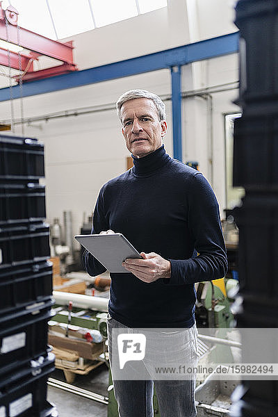 Confident male supervisor holding digital tablet in factory
