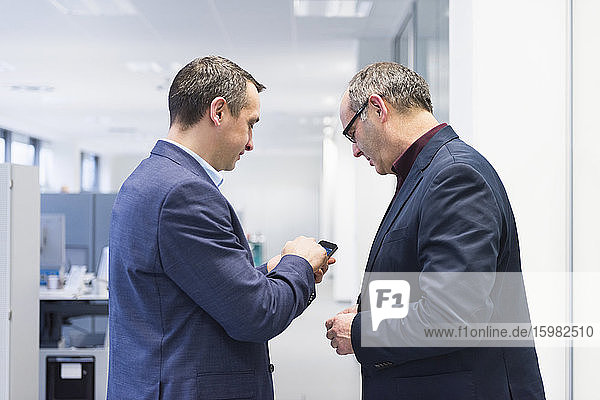 Zwei Geschäftsleute teilen sich ein Smartphone im Büro