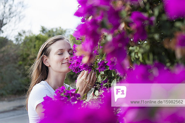 Porträt einer Frau mit geschlossenen Augen  die an lila Blüten riecht  Sardinien  Italien