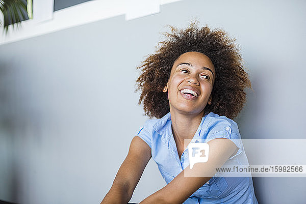 Unbekümmerte junge Frau  die sich lachend an die Wand lehnt